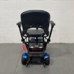 Rear View of a Drive Flex Automatic Folding Mobility Scooter. the Black Leatherette Captain's Seat with Armrests Wither Side is Elevated Above the Blue and Black Base with the Backrest Folded Up in a Seating Position. Attached to the Base of the Rear of the Scooter Are Anti-tip Wheels for Additional Stability. a Red Handbrake Lever is Also Visible That Can Be Used to Allow the Scooter to Be Free-wheeled if Broken Down. Drive Flex Autofold