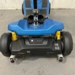 Close-up View of the Rear of a Li-tech Neon 15 Mobility Scooter. the Back Features a Blue Plastic Cover with a Prominent Li-tech Logo on the Black Bumper. Yellow Suspension Springs on Each Side Provide Contrast and Indicate the Scooter's Shock Absorption Capabilities. the Rear Wheels Have Solid Black Tires and Are Flanked by Anti-tip Wheels for Additional Safety. Li-tech Neon 15