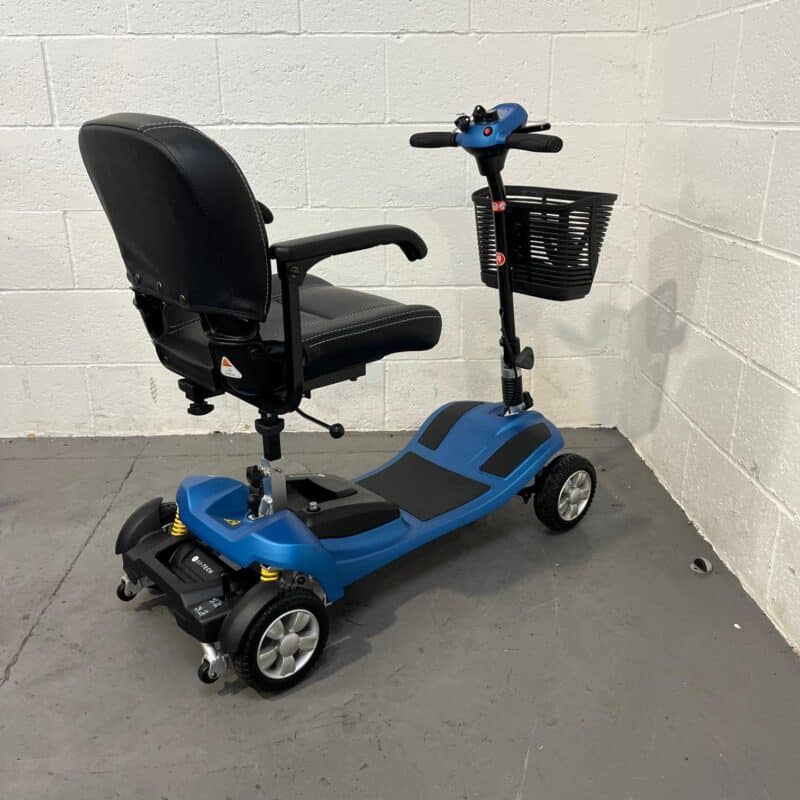 Rear and Right Side Perspective of a Li-tech Neon 15 Mobility Scooter. the Scooter Has a Bold Blue and Black Color Scheme, with an Adjustable Black Swivel Seat That Has a High Back and Headrest for Comfort. the Left Side Shows the Scooter's Control Tiller with a Black Wire Basket, Ergonomic Handle Grips, and the Control Panel with Red and Blue Buttons. the Scooter's Frame Has Yellow Shock Absorbers That Add a Pop of Color and Enhance the Vehicle's Suspension System. Li-tech Neon 15