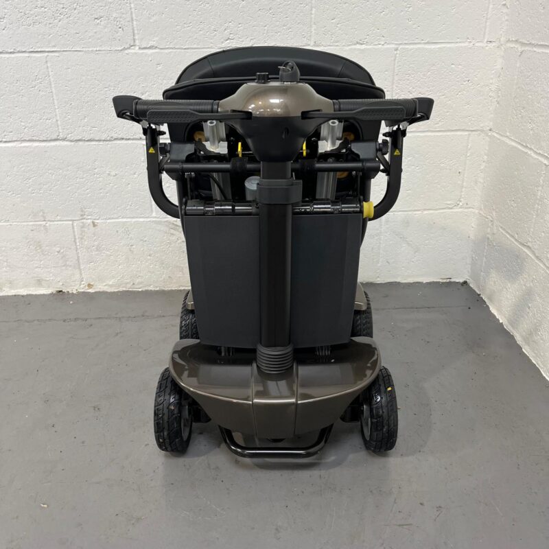 a Front View of a Folded Second-hand Gold and Black Globe Trotter Edrive Automatic Folding Mobility Scooter. One Rehab Globetrotter