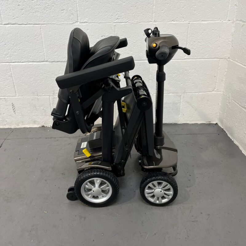 a Side-on View of a Folded Second-hand Gold and Black Globe Trotter Edrive Automatic Folding Mobility Scooter. One Rehab Globetrotter