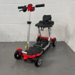 Photo Showing a Three-quarter View of the Left Side and Front of a Red and Black, Motion Healthcare Mlite Second-hand Mobility Scooter. Motion Healthcare Mlite